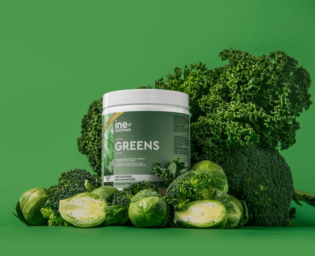 A container of ine+ nutrition Super Greens powder, unflavoured, with leafy fruits in the background.